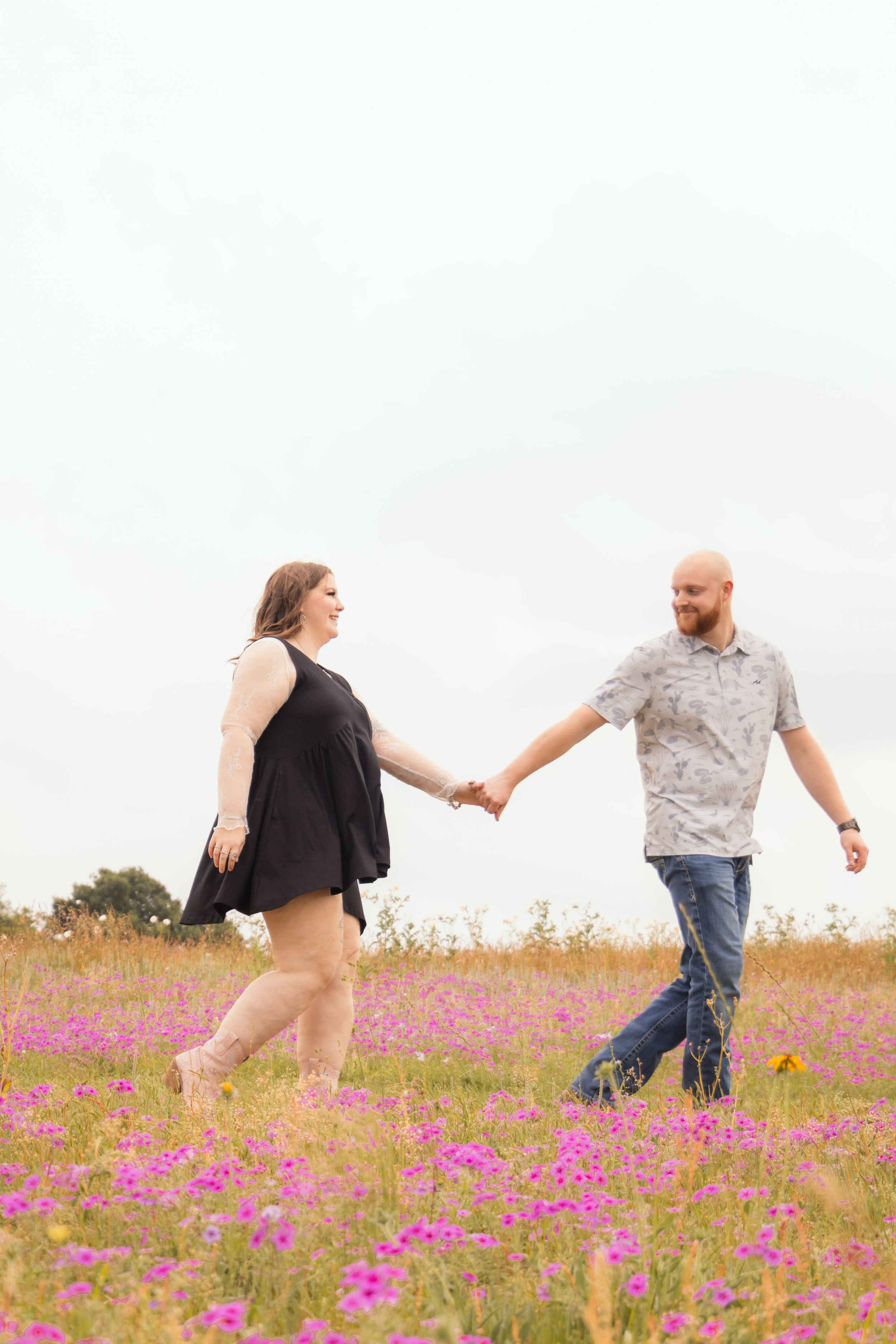 Man leading his girlfriend through a flower field, holding hands.