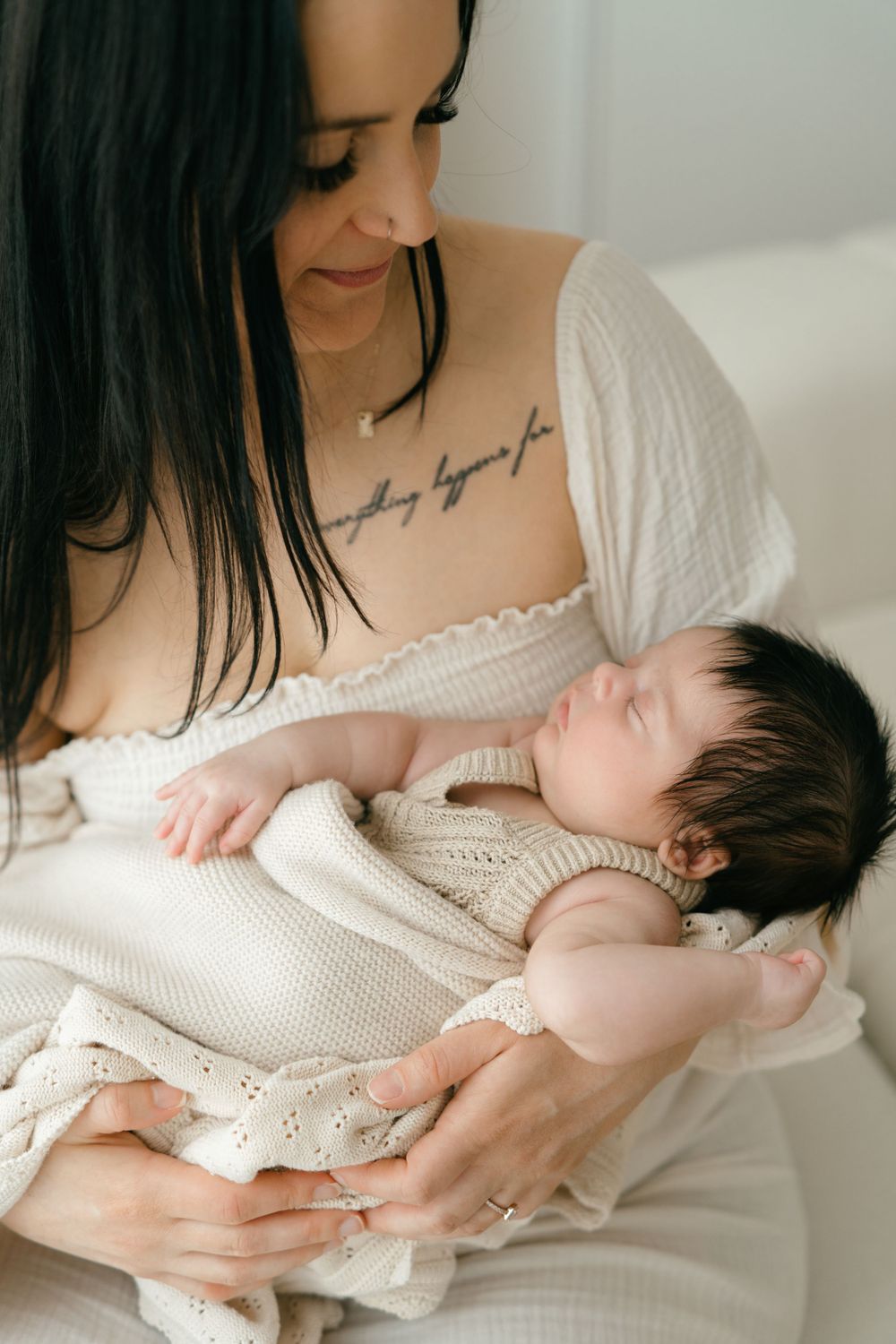 Newborn in white knit outfit sleeping peacefully against soft fabric.