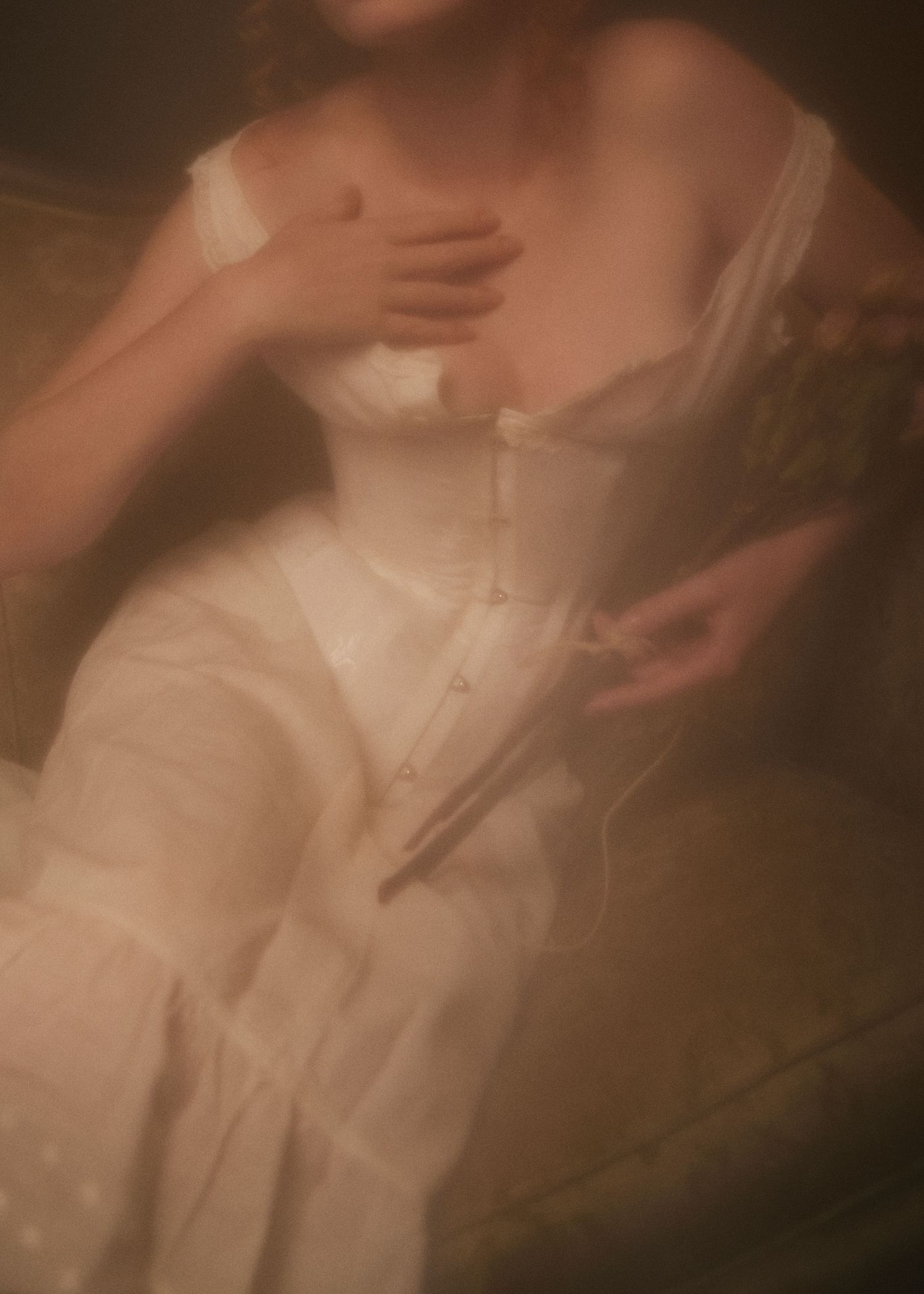 Ethereal figure in white corset dress captured in soft focus with dreamy sepia tones.