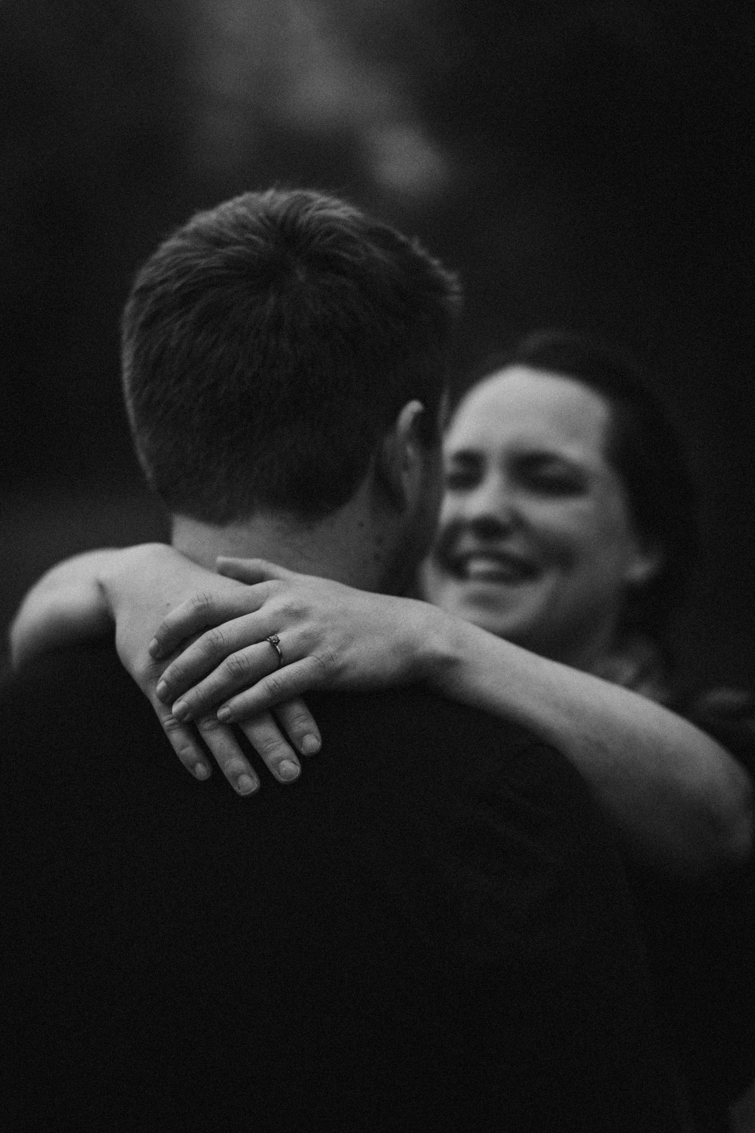 An intimate black and white photo captures a couple embracing in laughter.