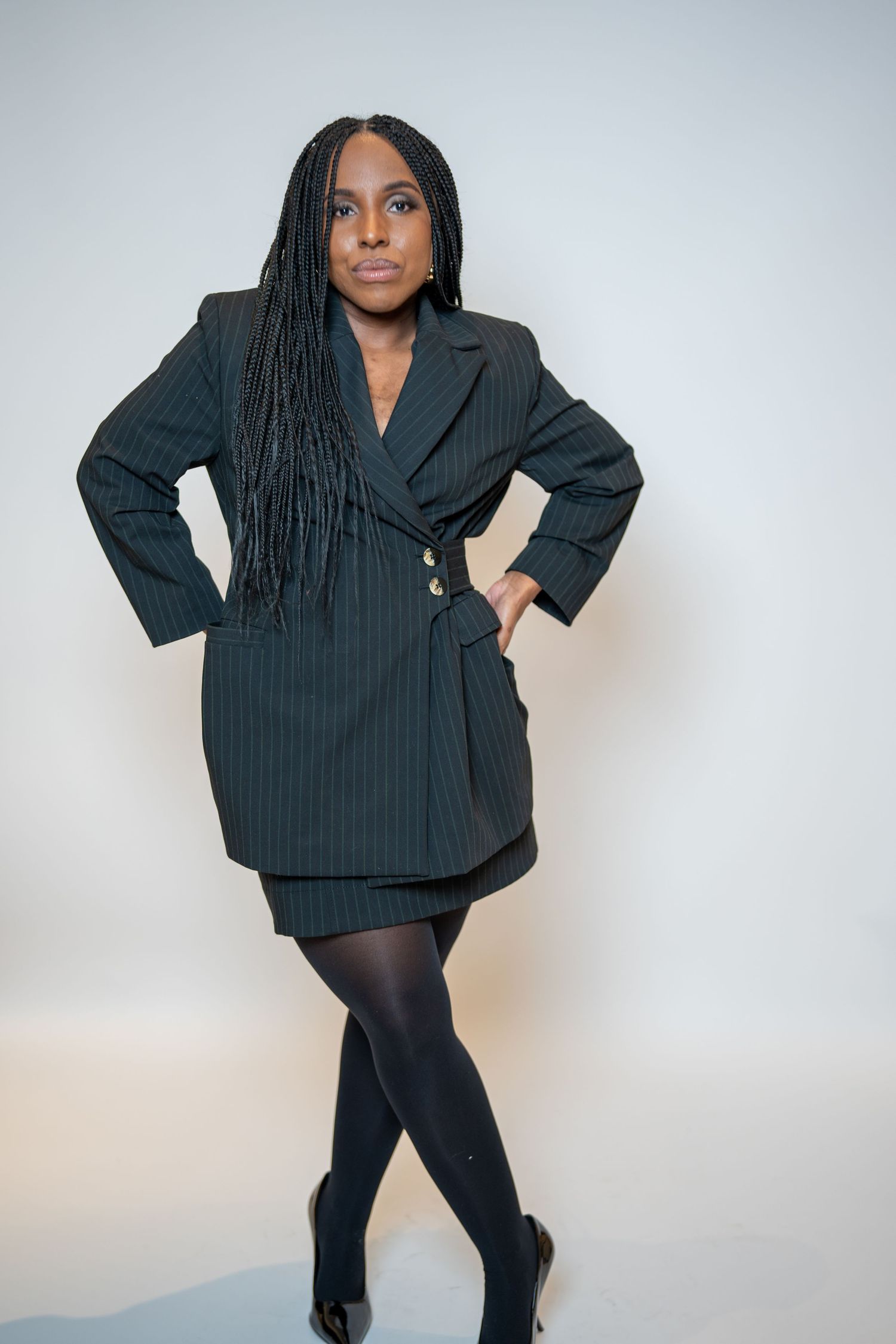 A set of fashion photos showing a black pinstripe blazer styled with black leggings and boots against a light background.