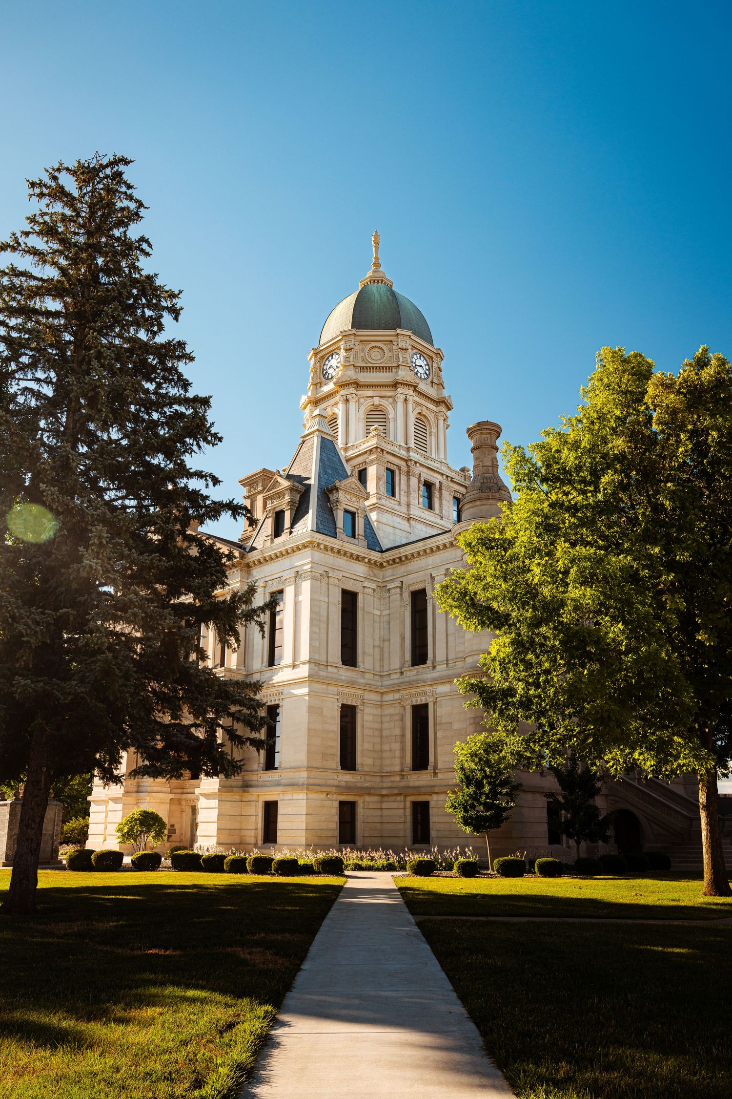 Historic courthouse building with ornate dome architecture and landscaped grounds on sunny day.