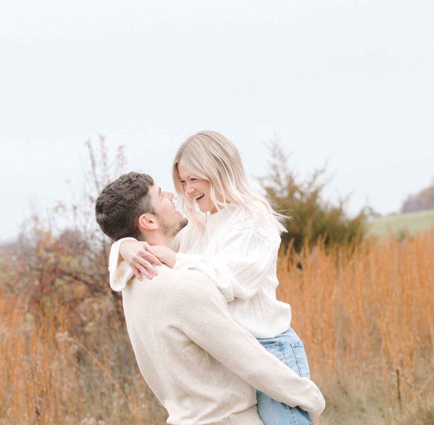 A couple shares intimate moments on a wooden dock overlooking a serene lake at sunset.