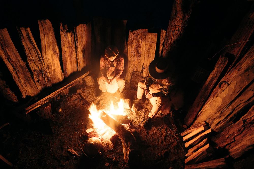 A cozy campfire burns brightly among wooden logs in the darkness.