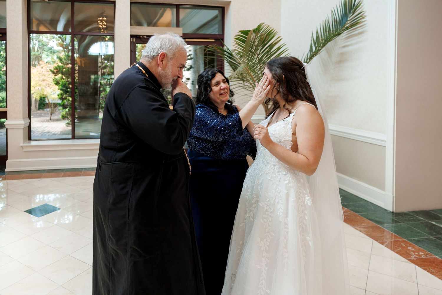 Emotional moment between bride and family members in church foyer.
