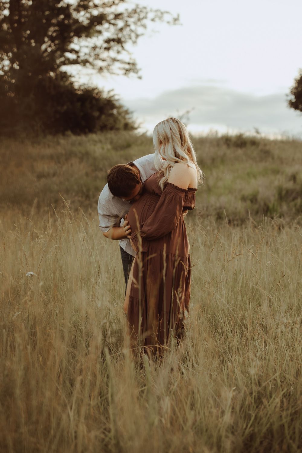 Romantic couple portrait session in rustic field during sunset.