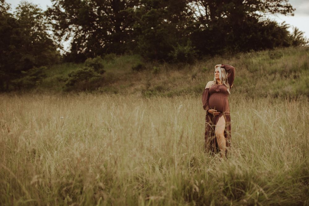 A couple walks hand in hand through a scenic grassy field during golden hour.