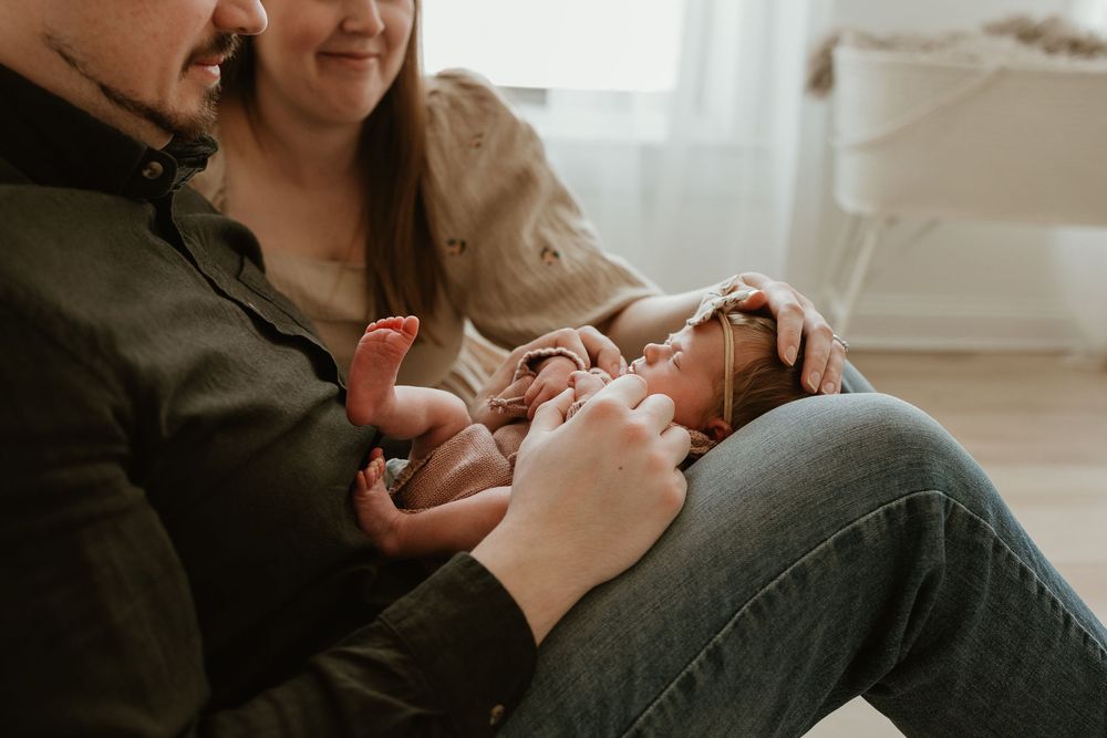 A tender moment captured in black and white as a parent cradles and kisses a newborn baby.