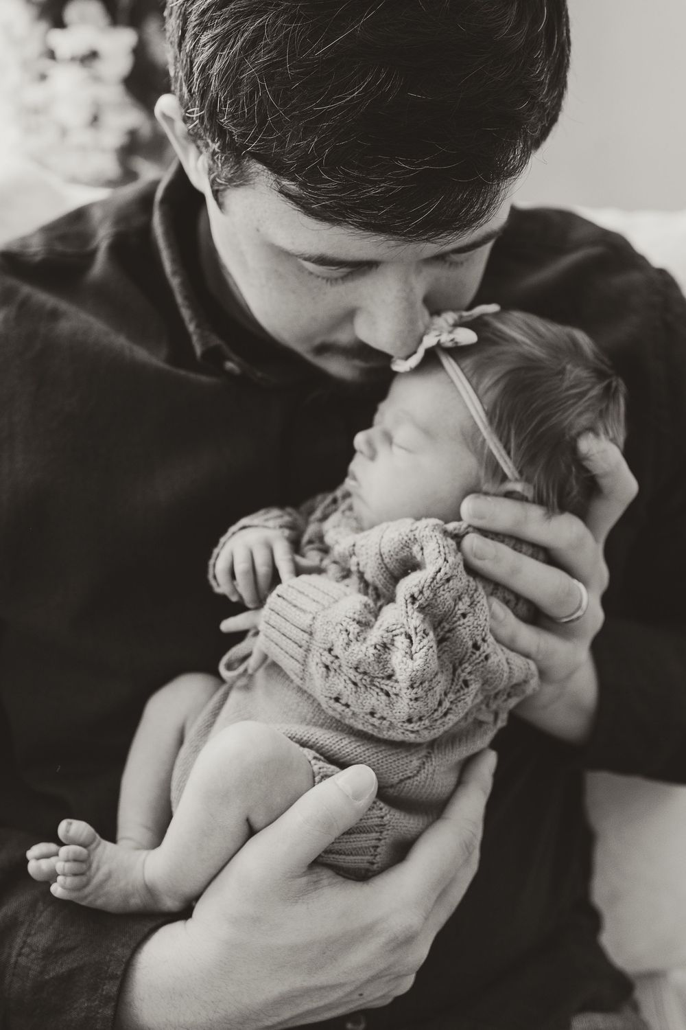A series of intimate black and white photos showing tender moments between a parent and newborn baby.