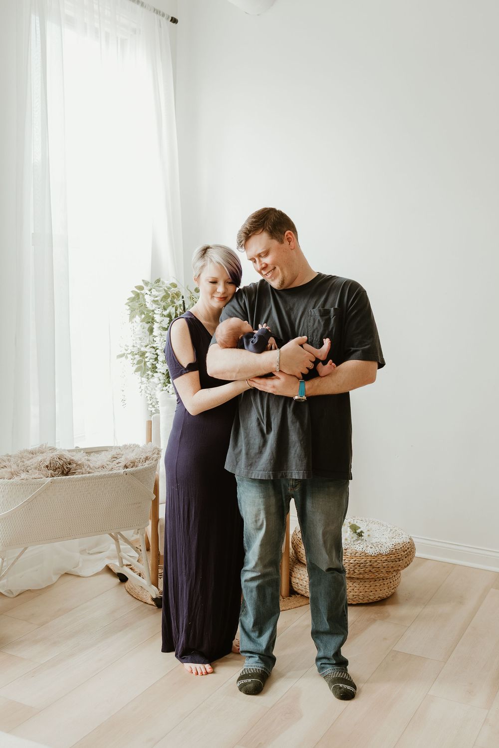 A couple dances together in a bright white room with light wood floors and minimal decor.