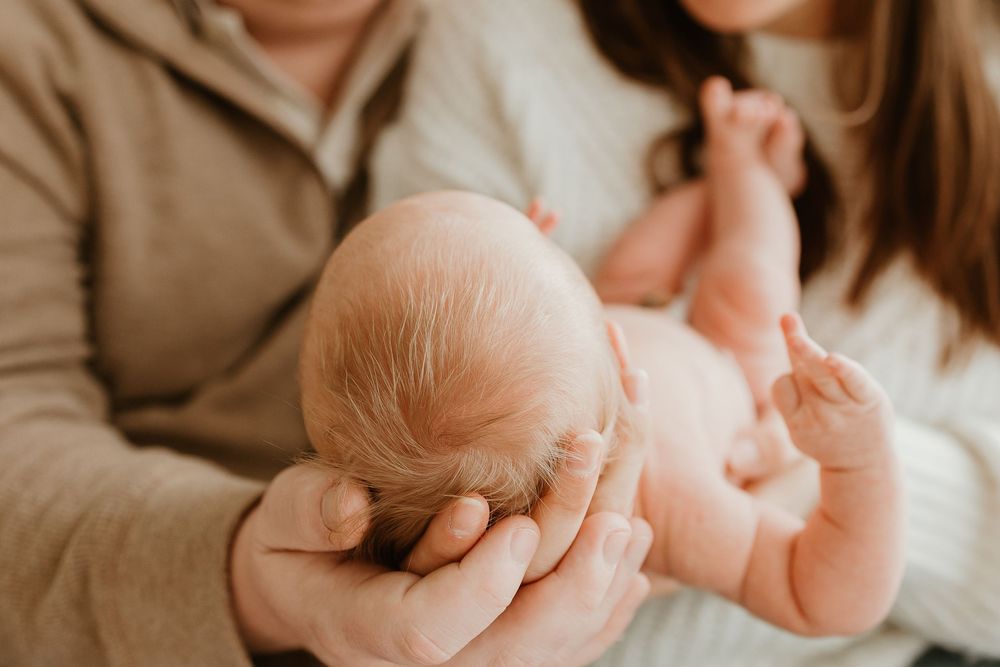 Tender black and white image of newborn baby's tiny feet being gently held in parent's hands.
