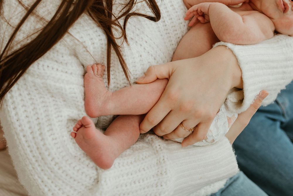 Close-up view of tiny newborn baby feet resting on soft white knitted blanket.