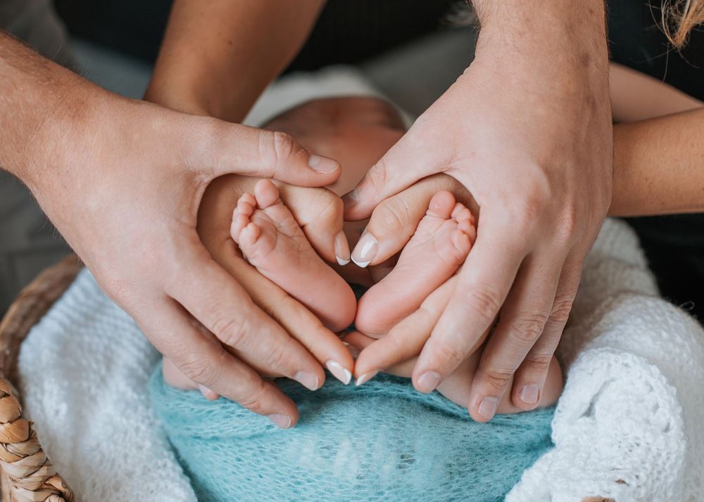 Close Detail shot of parent's hands holding newborn baby's feet.