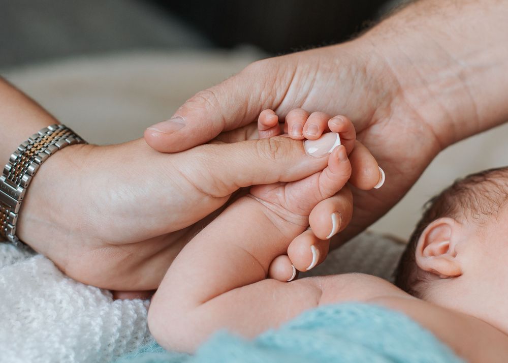 Close Detail shot of parent's hands holding newborn baby's hand.