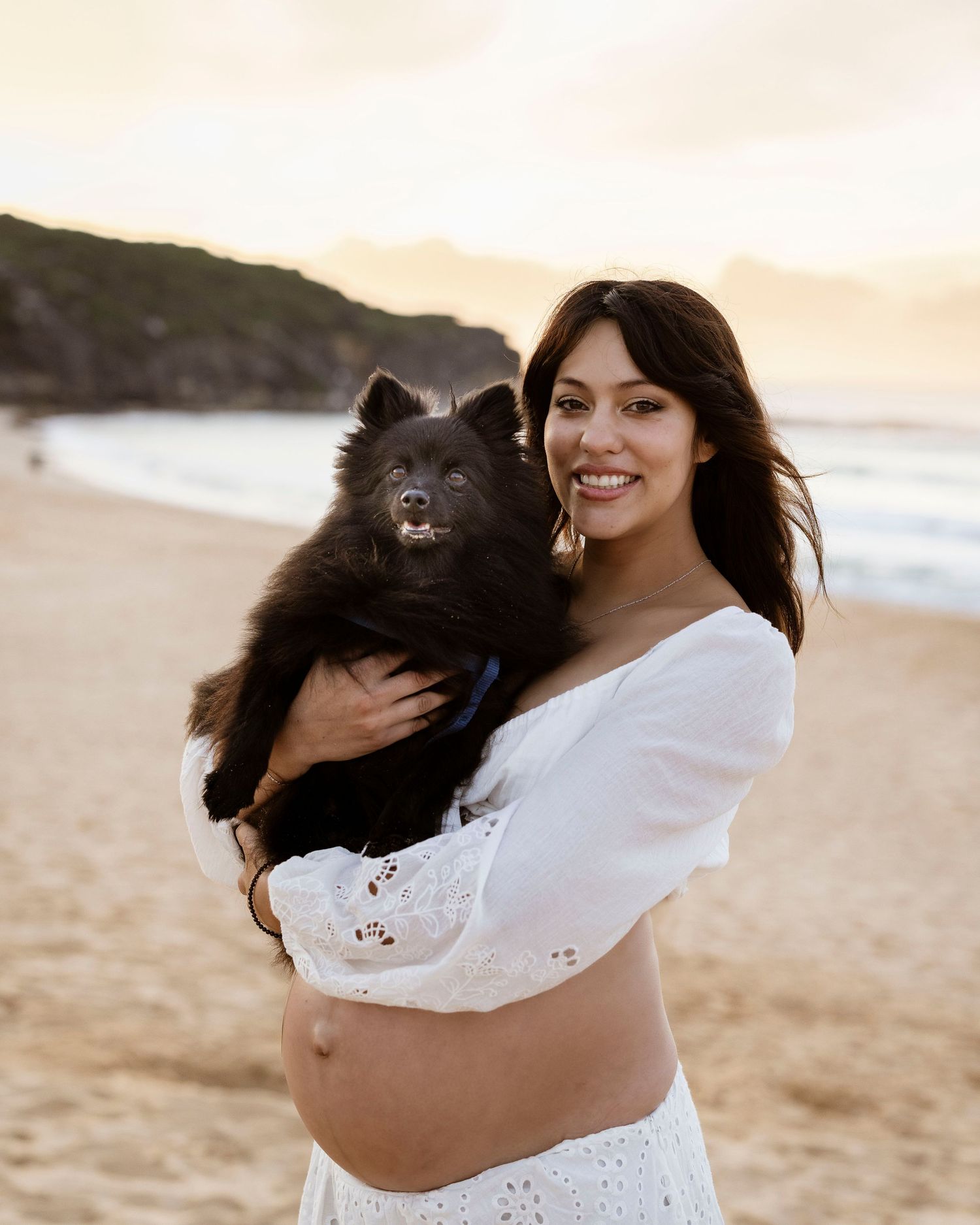 pregnant mama holding her pet during her sunrise maternity photoshoot at Curl Curl Beach