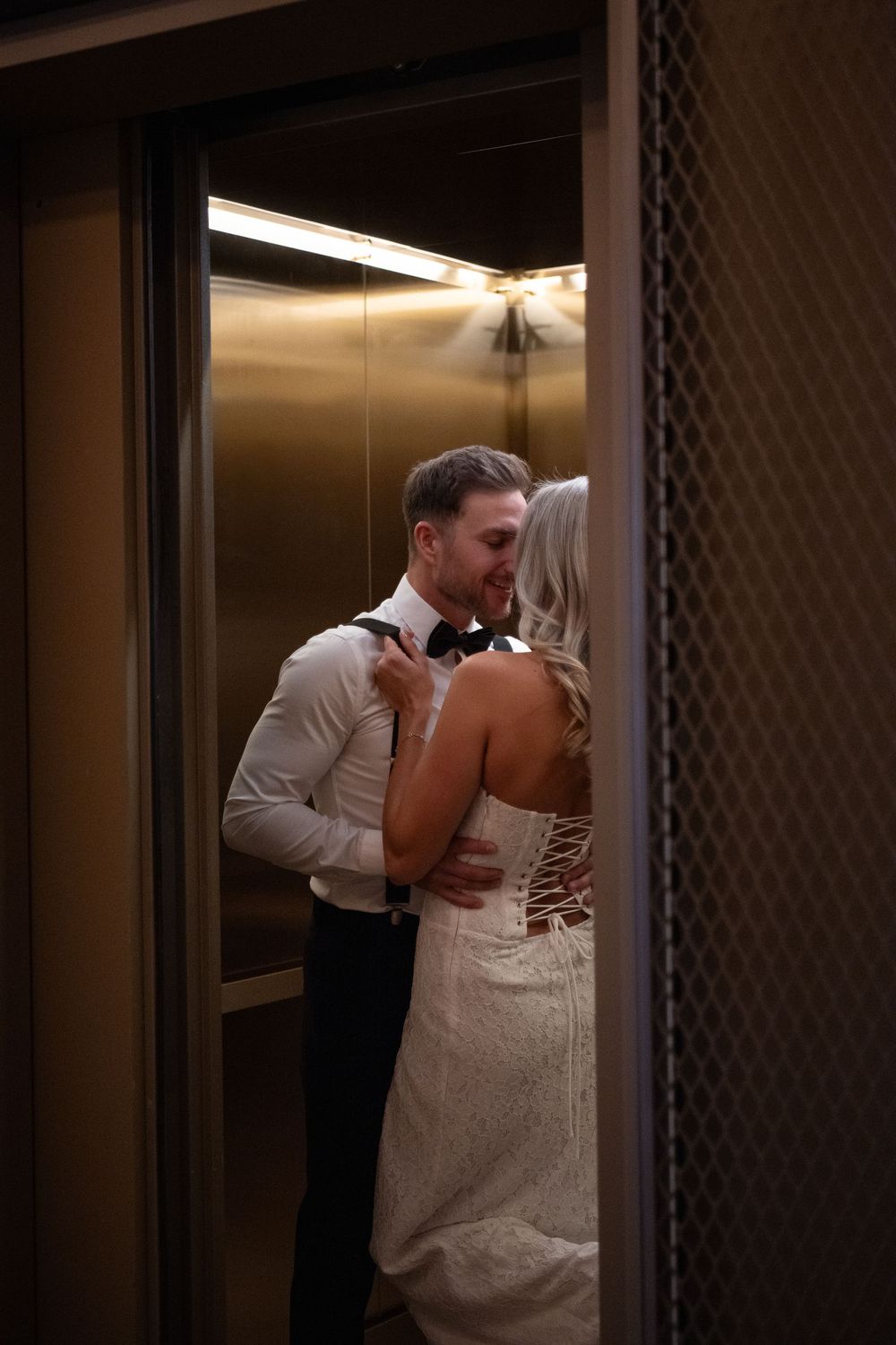 A romantic moment captured as a couple in wedding attire share a kiss in an elevator.