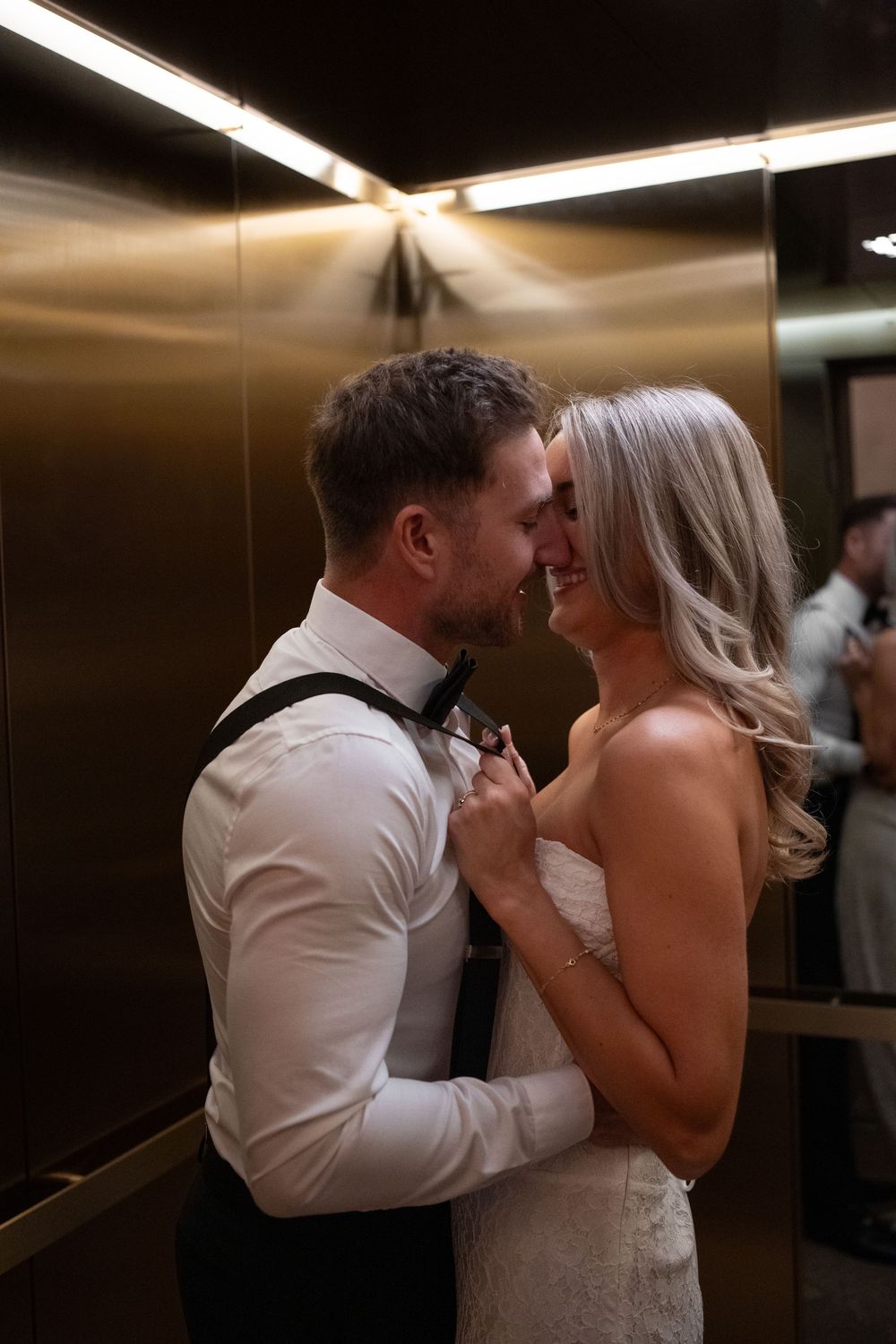 A couple shares an intimate moment while dancing together in a dimly lit elevator.
