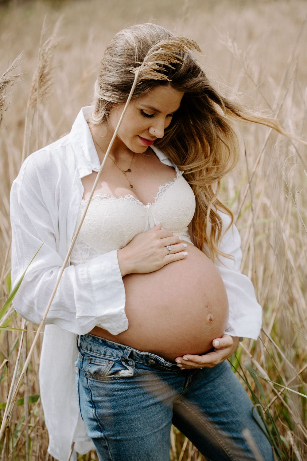 Maternity photoshoot in tall grass field showing progression of tender moments.