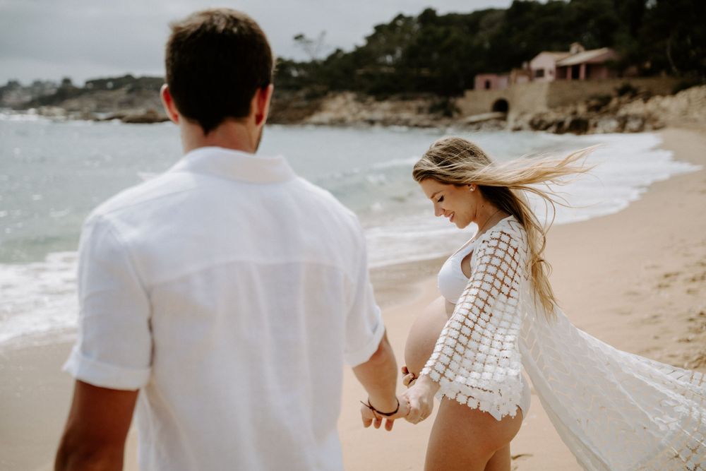 Romantic beach photoshoot with couple walking along sandy shoreline.
