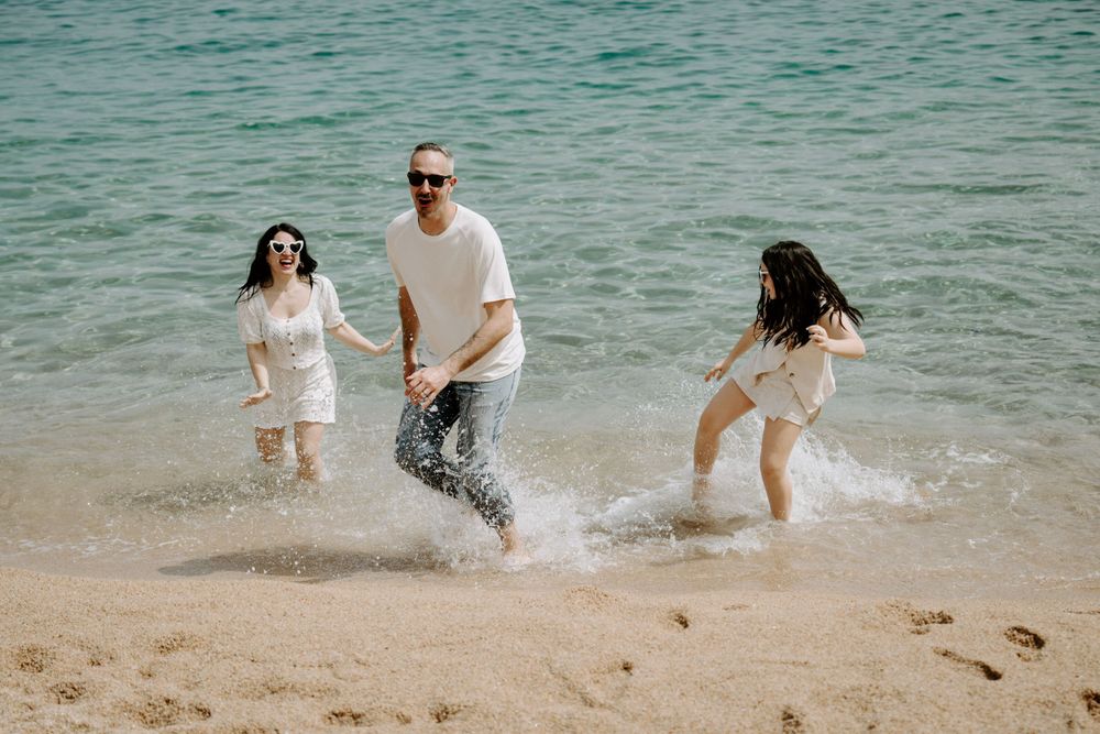 Couple playing and splashing in turquoise ocean water at the beach during a romantic photoshoot.