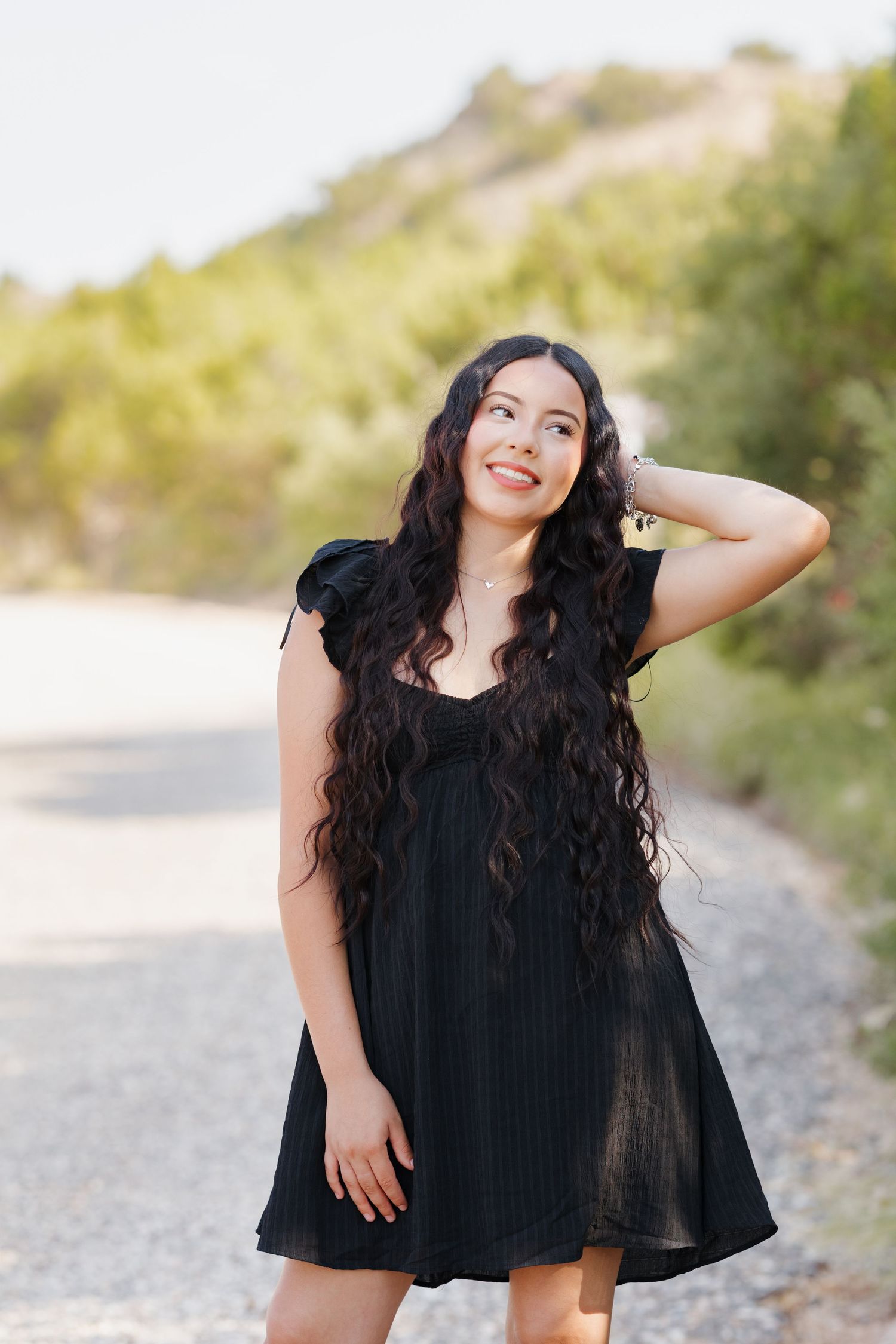 A pregnant woman in an orange tulle maternity gown poses in a lush green park.