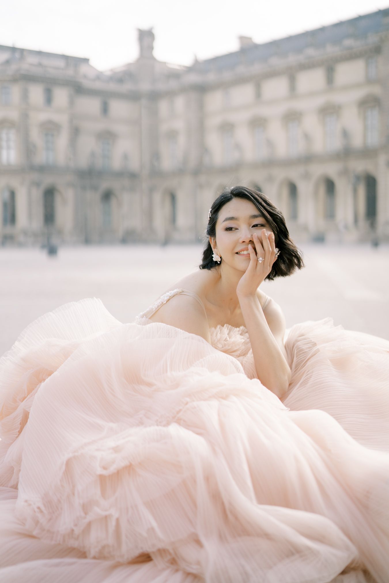 Person in flowing pink tulle gown posing outside historic European building.