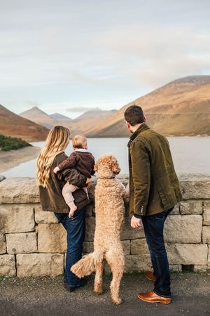 A family and their goldendoodle dog looking out over a mountain lake.