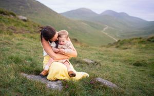 A tender embrace shared in a yellow dress against misty mountain slopes.