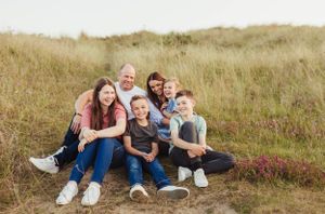 Family laying together on grassy hillside during outdoor photo session.