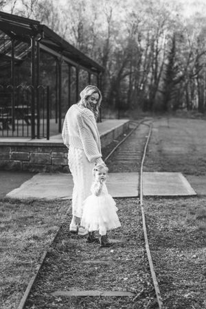A tender moment captured in black and white by train tracks near a vintage station platform.