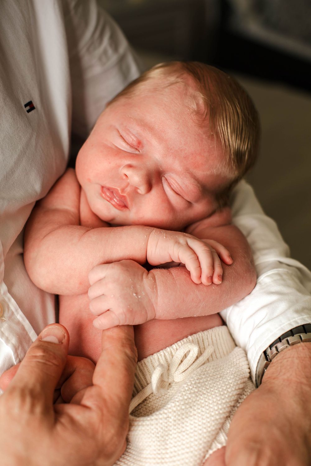 A peaceful newborn baby sleeping soundly on soft white fabric.