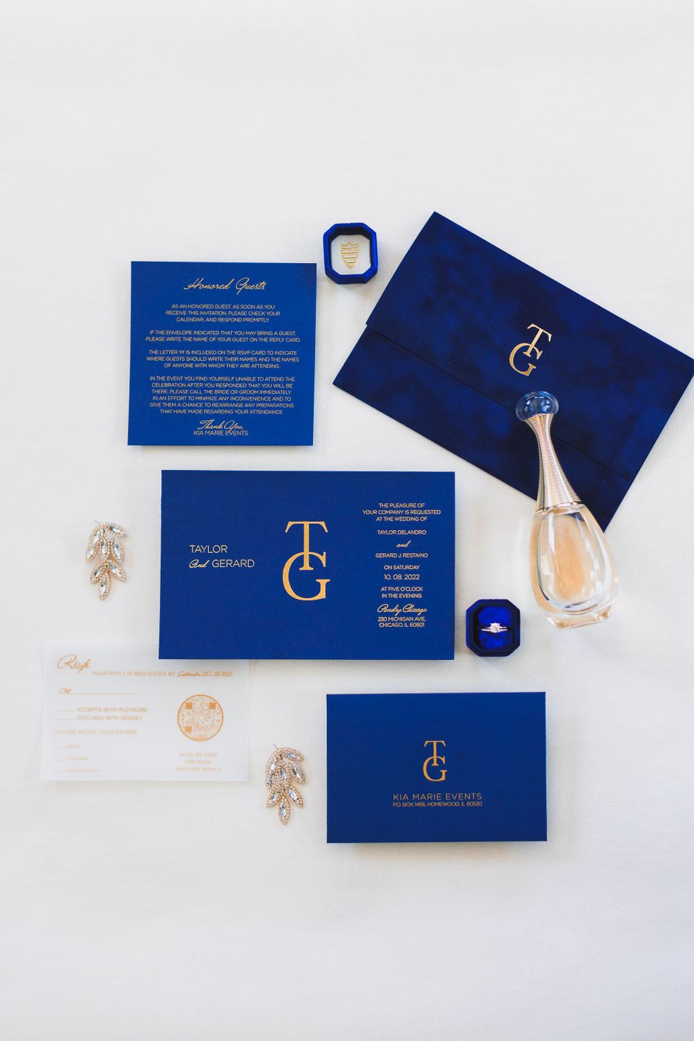 Luxury navy blue wedding invitation suite with perfume bottle and gold accents on white background.