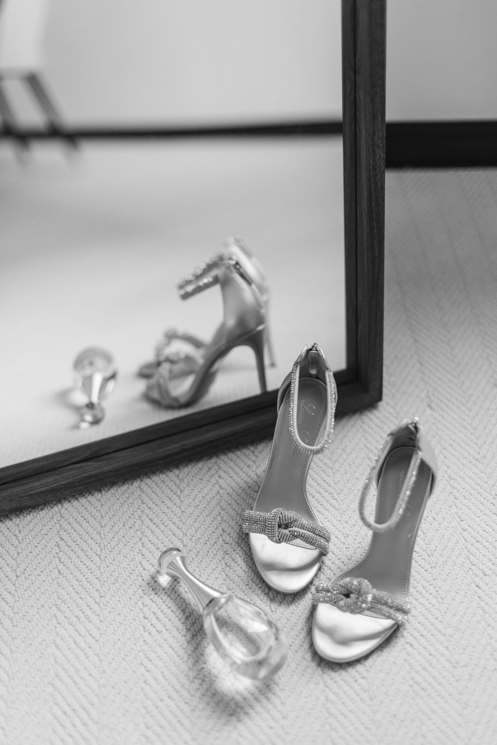 Elegant bridal shoes reflected in mirror with artistic black and white composition.