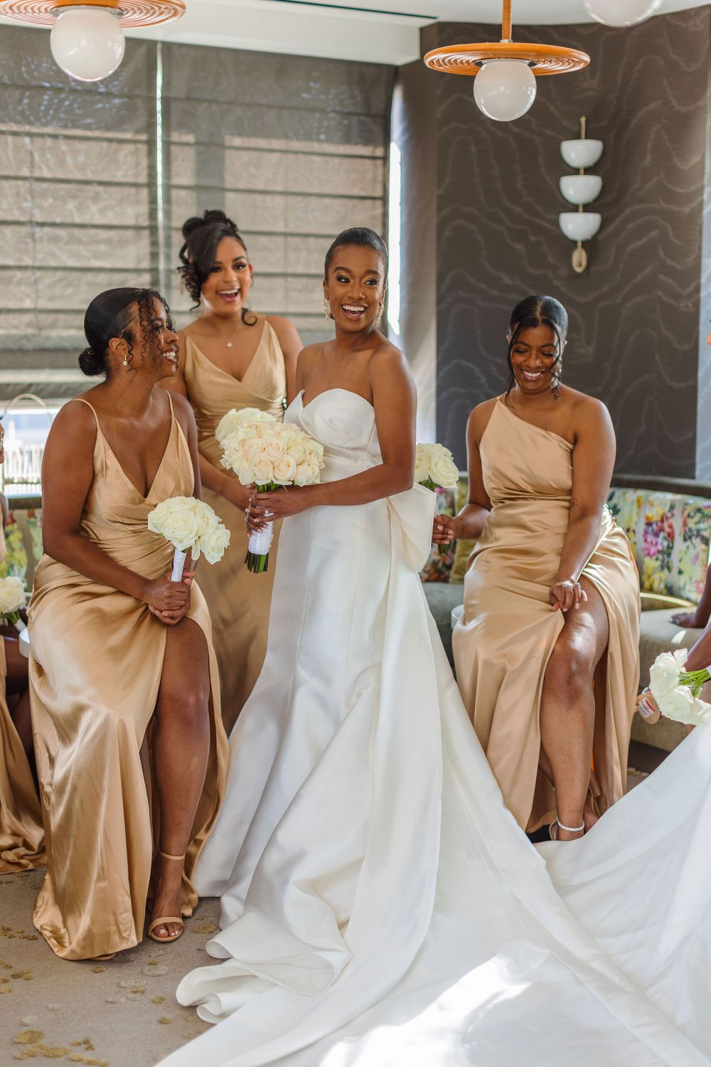 Wedding party in champagne dresses posing with bride in elegant white gown.