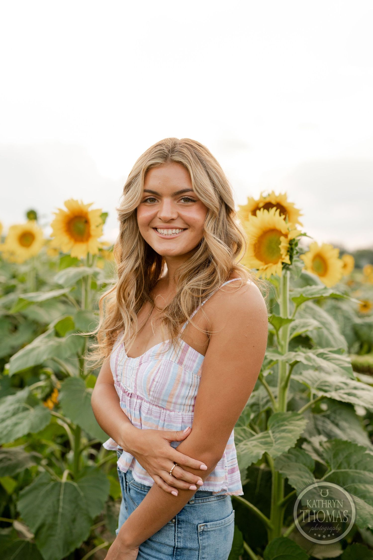 Summer portrait surrounded by bright yellow sunflowers with soft natural lighting.
