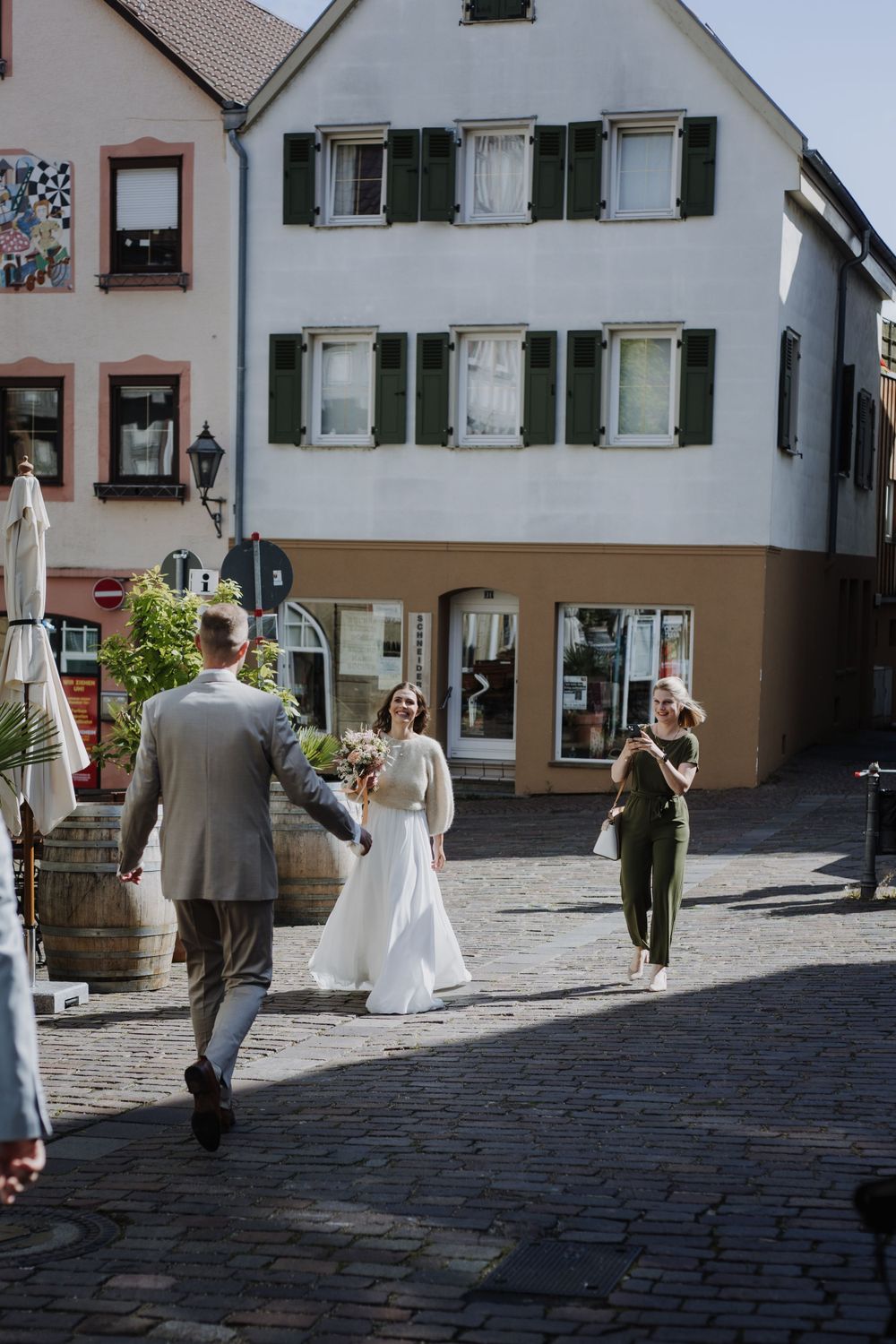 Couple walking on cobblestone street in front of traditional European buildings.
