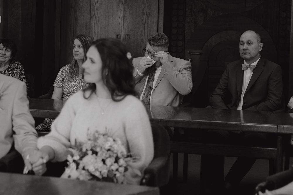 Black and white photo of wedding guests seated in wooden pews.