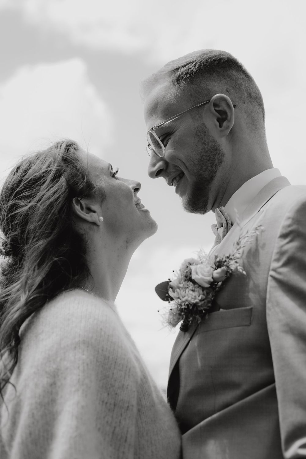 A romantic black and white portrait of a couple sharing a tender moment in their wedding attire.