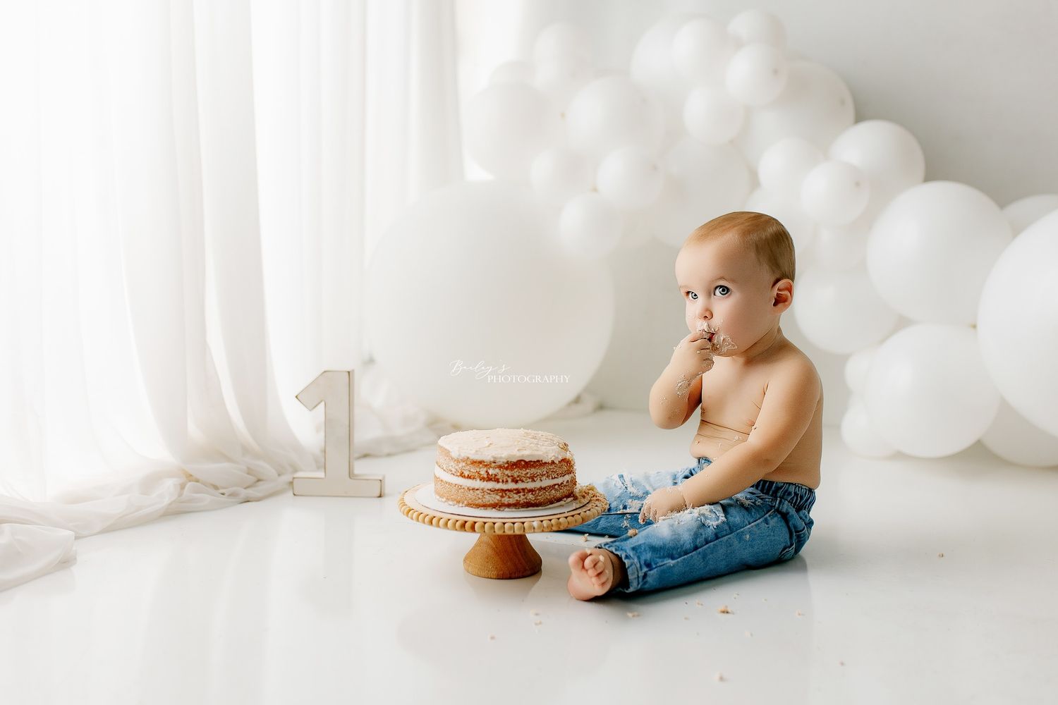 Cake smash photographer in Portsmouth OH capturing a joyful first birthday session in a luxury studio with custom themed setup