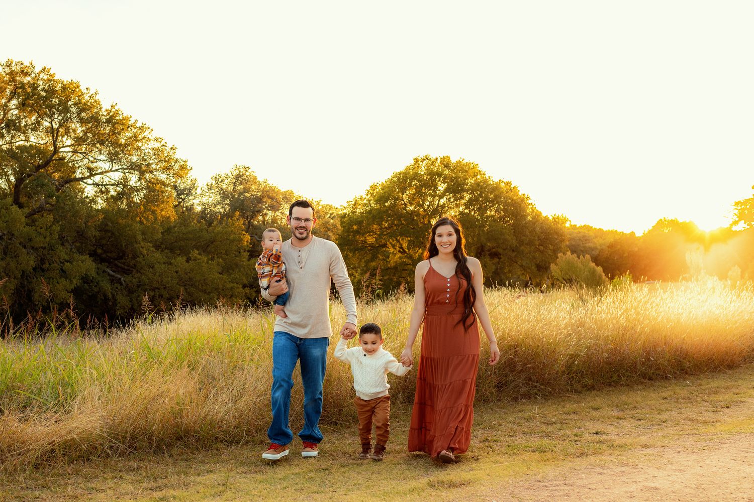 A family poses during golden hour, in a meadow in cedar park tx