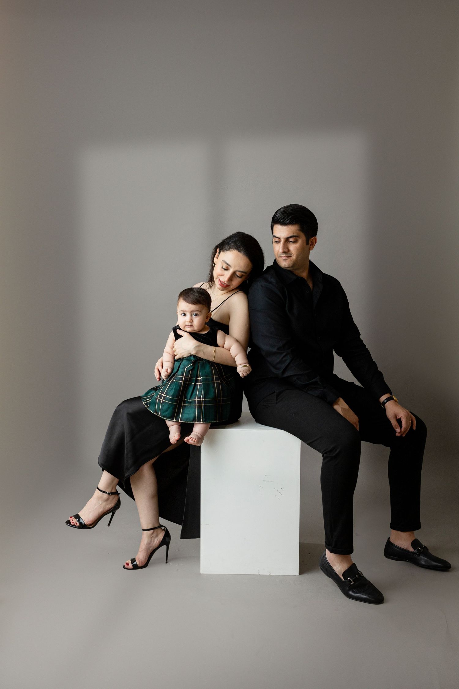 Modern minimalist family portrait against grey backdrop with white cube seating.