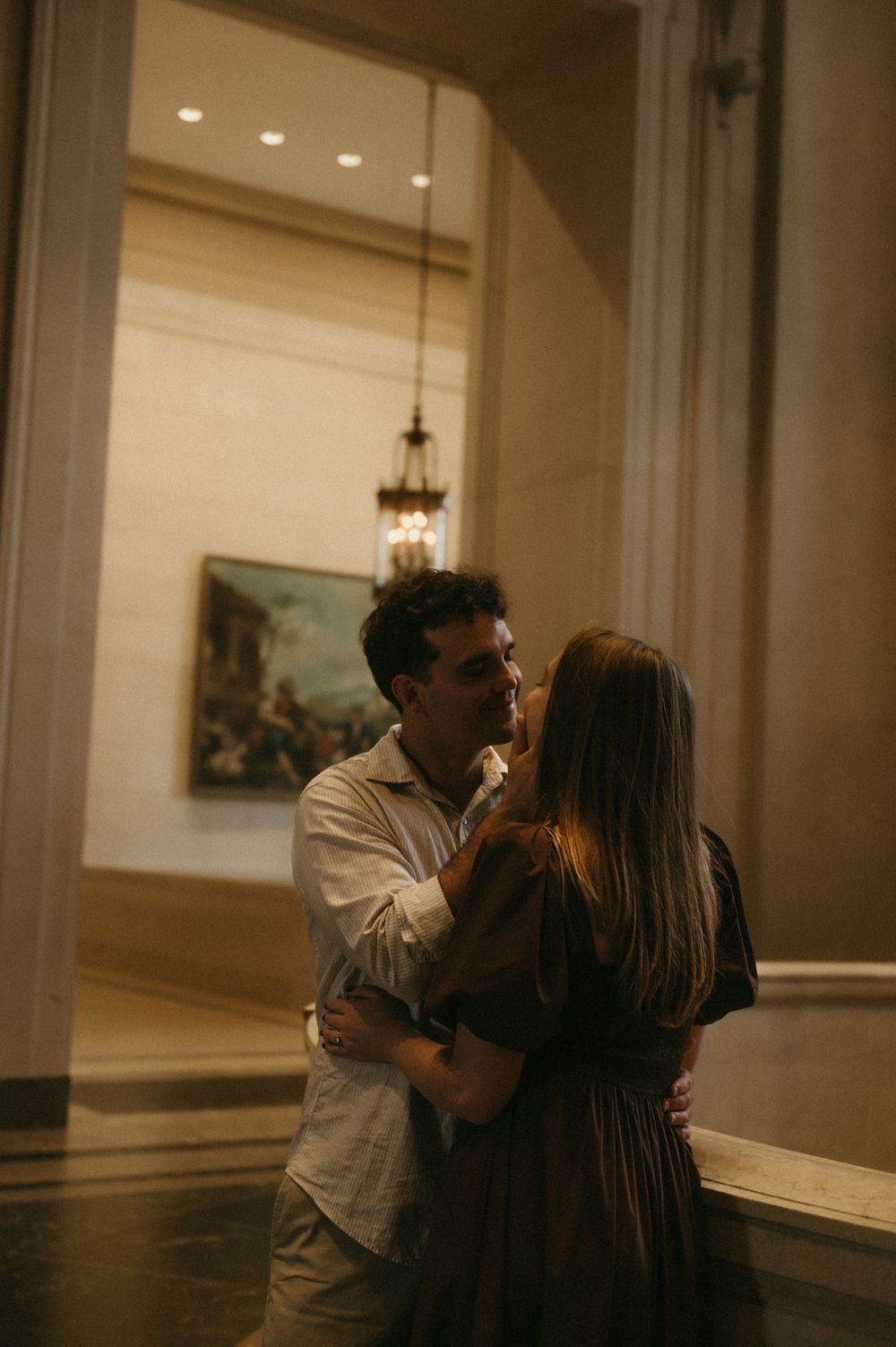 A romantic moment shared between two people in a dimly lit museum gallery.
