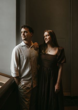 Artistic black and white photograph showing silhouettes in an intimate indoor setting with moody lighting.