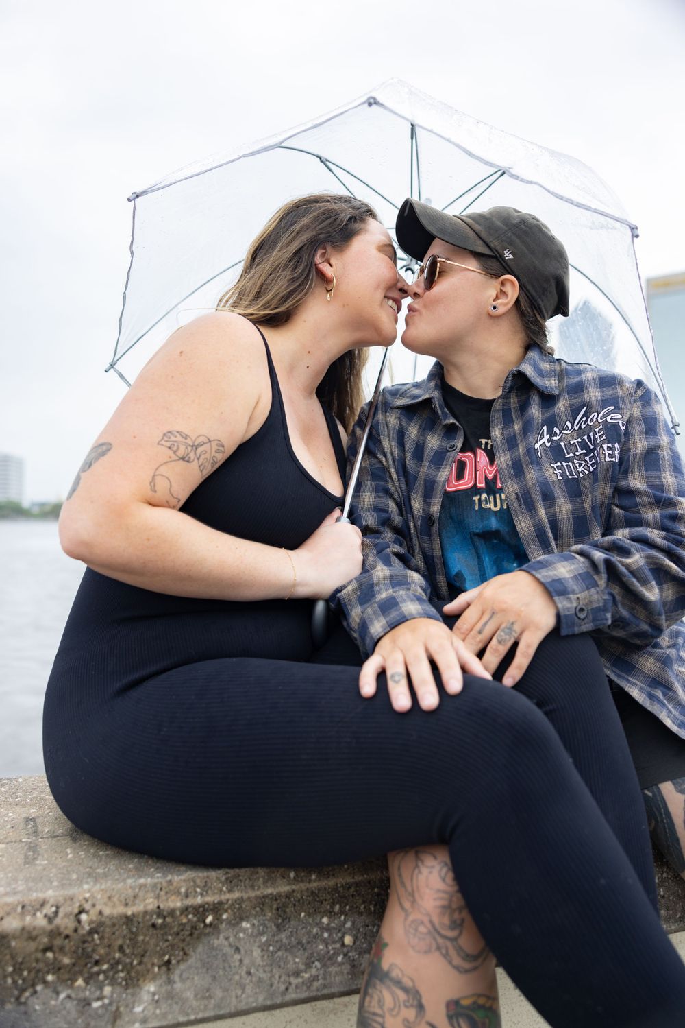 Couple sharing tender moment under clear umbrella in urban setting.