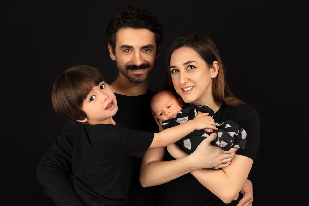 Family portrait of parents with children against black background.