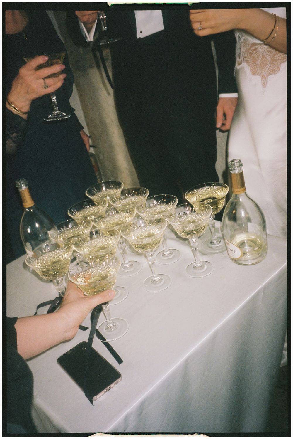 Champagne glasses arranged on a white tablecloth with bottles of bubbly being served at an elegant celebration.
