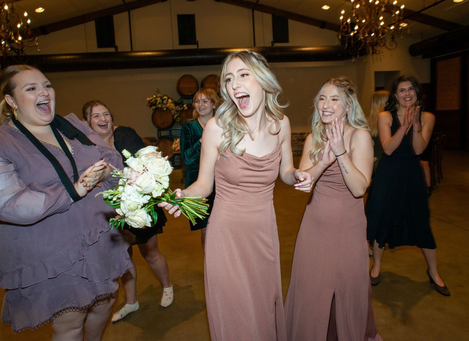 Bridesmaids in pink dresses celebrating joyfully at a wedding reception.