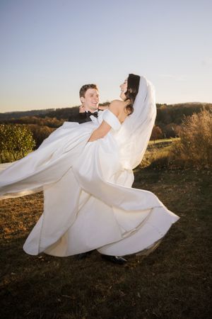 Groom spinning his bride around during sunset