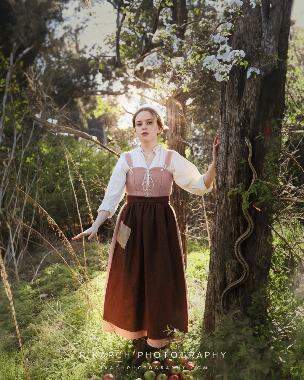A period costume portrait shows someone in a white blouse and pink bodice amidst flowering trees.