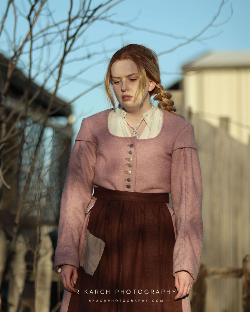 A historical costume portrait shows someone in a dusty pink dress with buttons and brown skirt.
